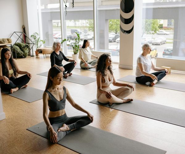 Group of diverse people sitting calmly on yoga mats.